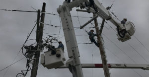Utility-workers-in-cranes-working-on-telephone-poles
